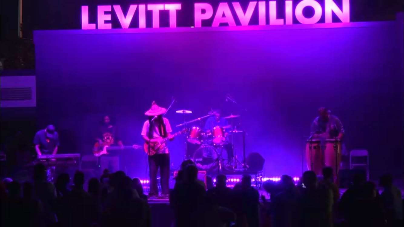 One Love Reggae Band performing on stage at Levitt Pavilion under purple lights with the crowd in front