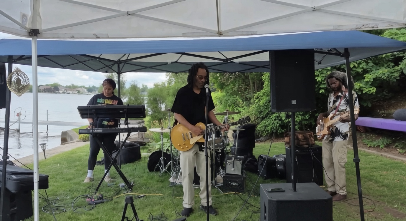 One Love Reggae Band playing under a white tent by the lake at a private birthday party, June 2026