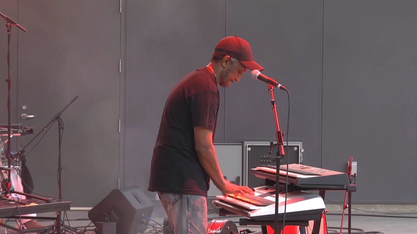 Keyboardist in a red cap playing on a hazy stage